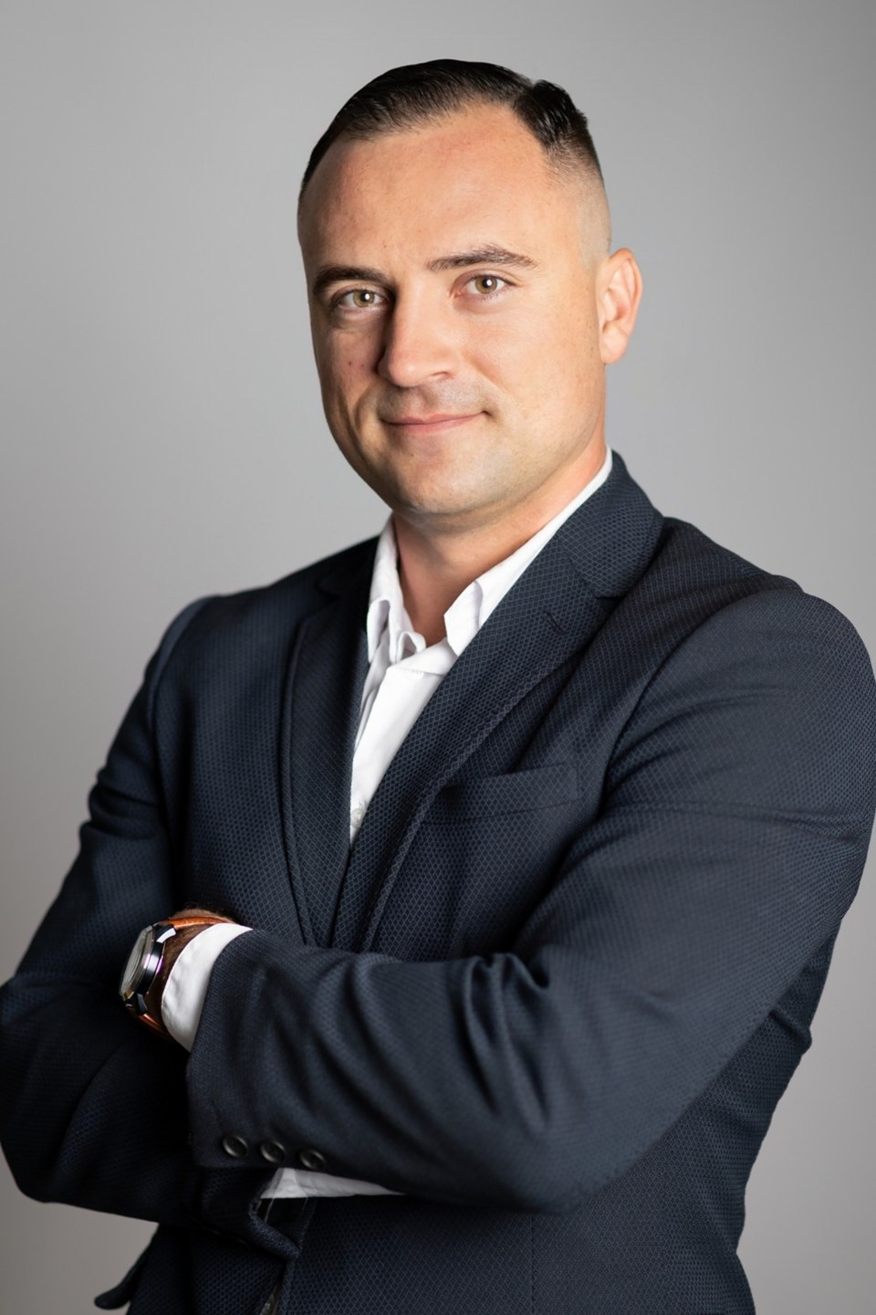 Bartłomiej Heichel, portret w ciemnej marynarce, z założonymi rękami, na szarym tle